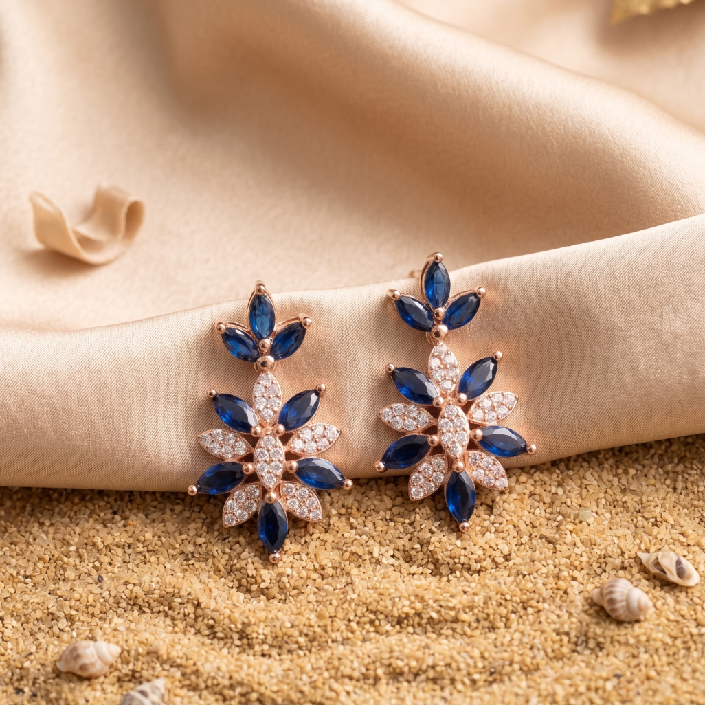 Hands paint the design of a necklace with a blue stone in the center; on the table are a palette and paints.